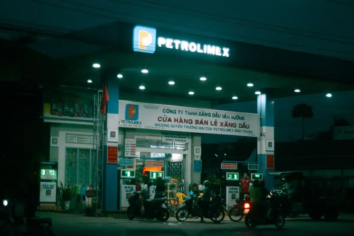 A fuel pump display showing climbing price numbers, with a blurred African city or town in the background, symbolizing the real-world impact of rising energy costs on everyday consumers across the continent.