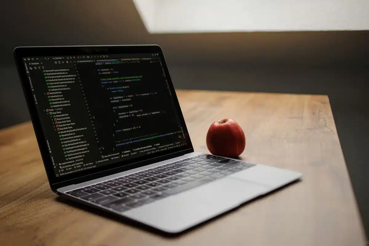 A laptop displaying glowing code on a dark background, an open-source symbol or file tree visible on screen, a coffee cup nearby, cool blue-green lighting suggesting cost-efficient computing