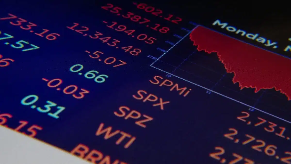 Stock market ticker displaying numbers and percentages in red and green, candlestick chart patterns descending, abstract financial data streaming across a dark screen