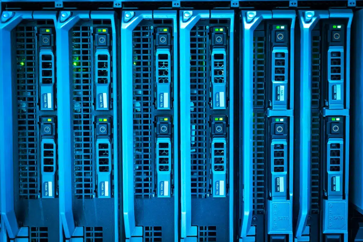 A data center interior with rows of server racks glowing with blue and green indicator lights, representing the massive infrastructure investment required for AI.
