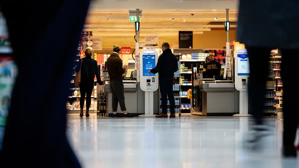 Retail store interior with digital checkout stations and self-service kiosks, customers shopping | modern retail technology
