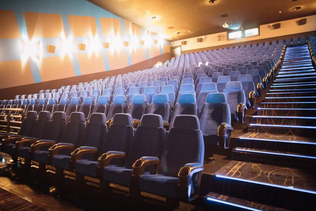 An IMAX theater screen showing an epic landscape scene with dramatic lighting and scale, viewed from empty theater seats in the foreground.
