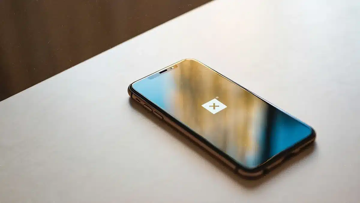 Apple logo reflected on a glowing smartphone screen in a minimalist tech environment with soft blue and white lighting | Apple product display