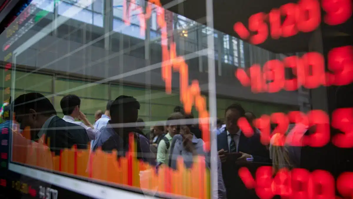 Stock market display showing red decline, financial charts and data streaming, glass building reflecting market activity | stock market trading floor