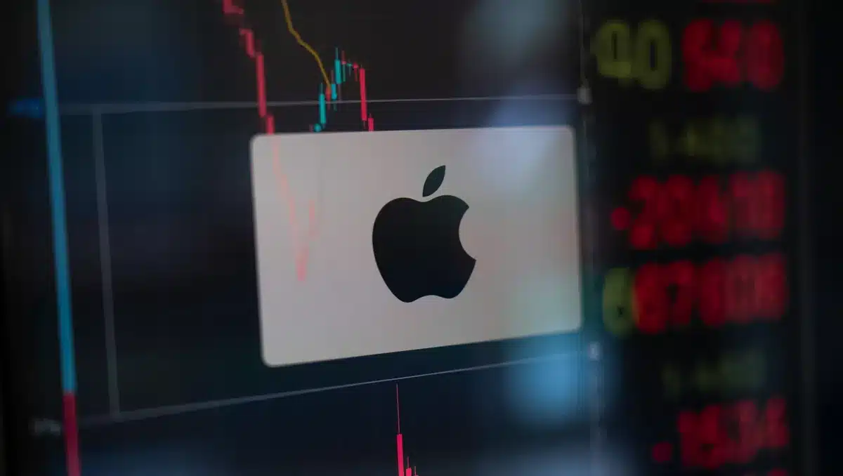 Stock market screen displaying Apple ticker with downward trend line, red numbers, candlestick charts in dim trading floor light | stock market trading screen