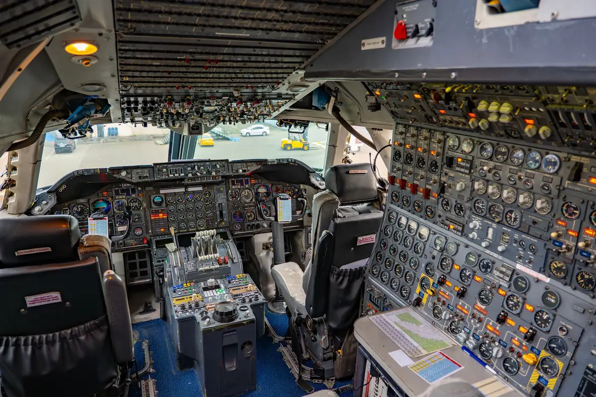An interior view of a modern aircraft cabin with advanced control panels and displays visible, showing secure communication equipment typical of government aircraft, with no identifiable personnel