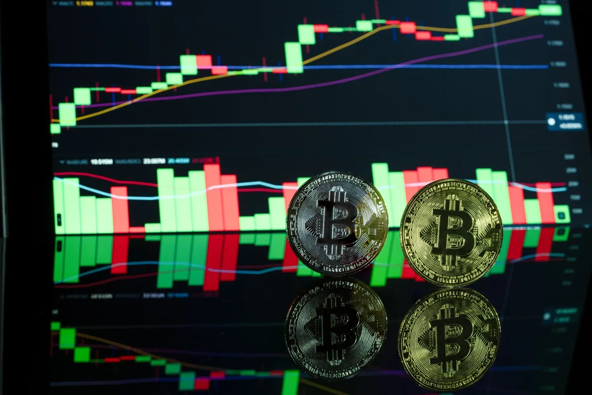 A glowing cryptocurrency coin symbol on a dark screen with blurred financial charts in the background, harsh blue-red lighting suggesting market volatility, numbers scrolling out of focus
