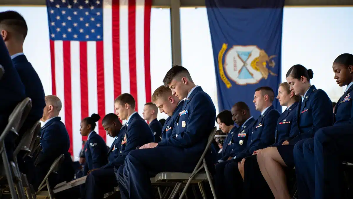 Military personnel in uniform seated in formal ceremony, flags in background, solemn atmosphere | Armed forces memorial service