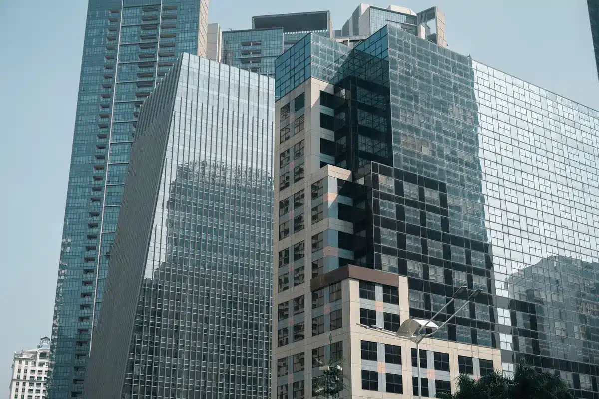 A modern institutional real estate office with glass walls, a view of a portfolio of restaurant properties on a digital screen, sunlight streaming through windows