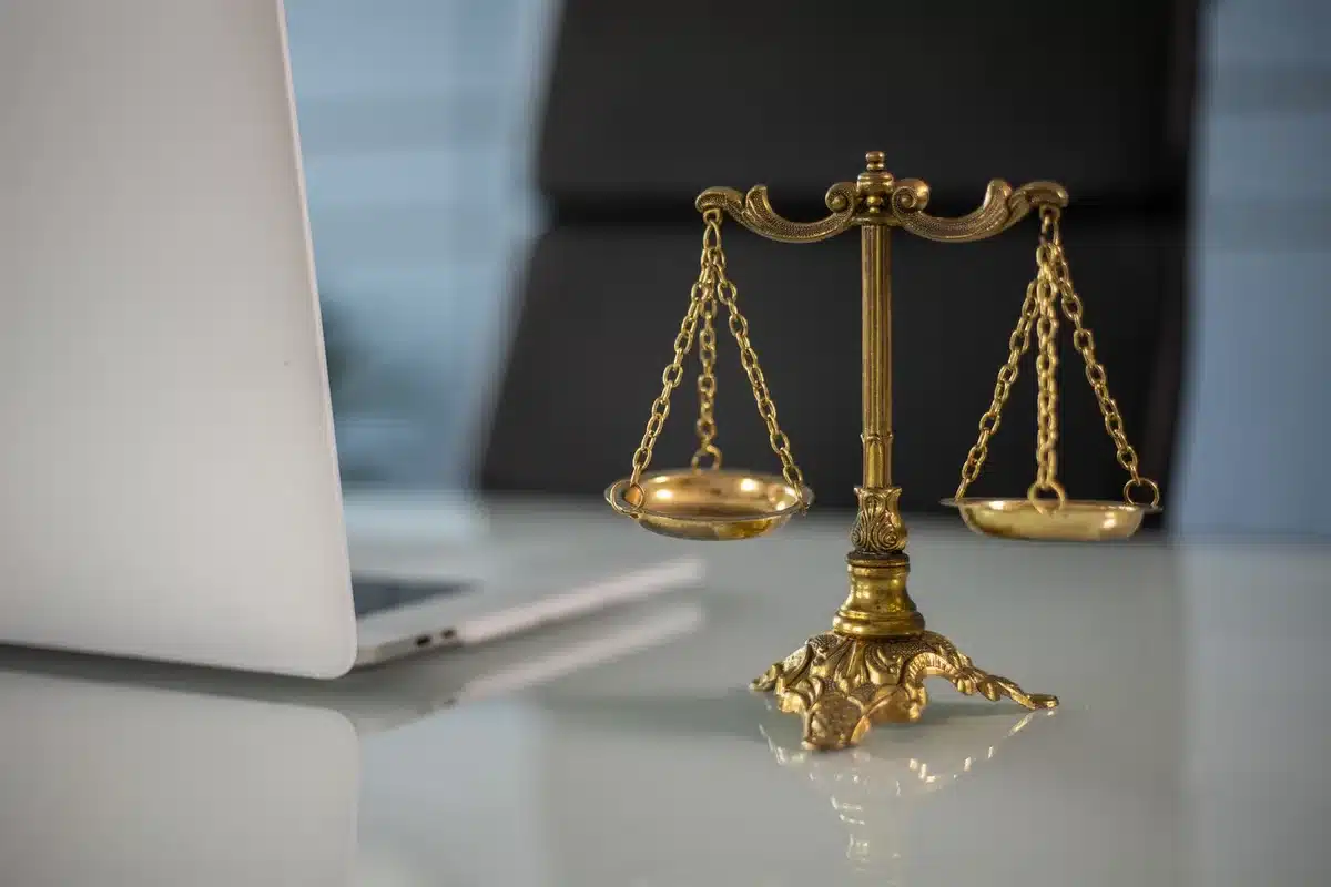 A gavel resting on a desk in an empty courtroom, harsh overhead lighting casting sharp shadows, legal documents stacked nearby, the room devoid of people
