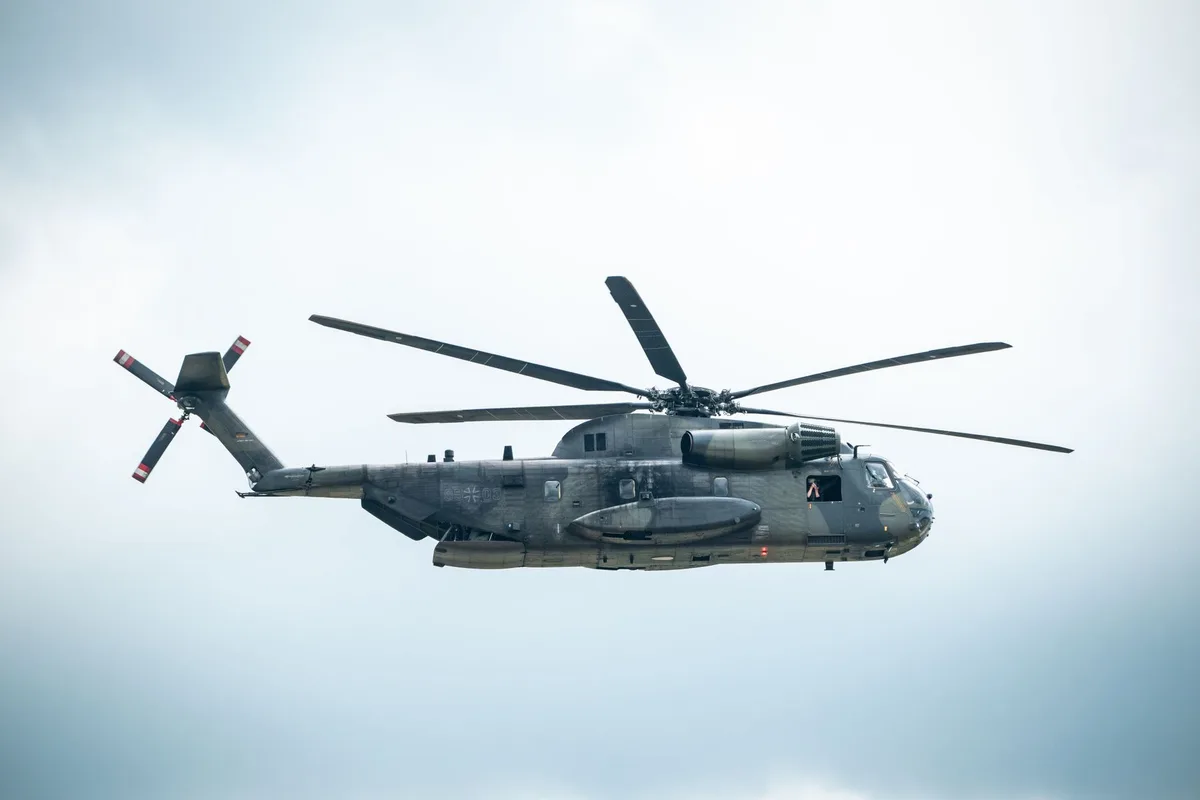 A military transport aircraft in flight against a clear sky, viewed from below, emphasizing the scale and capability of modern airlift operations.