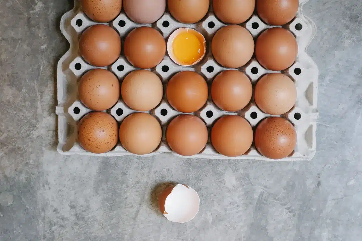 A close-up of an egg being cracked open into a bowl, with the yolk visible. Neutral kitchen setting.