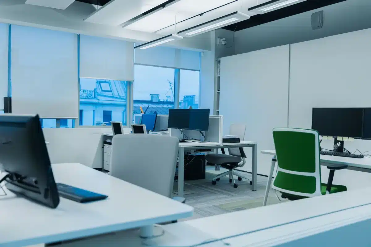 An empty office chair at a trading desk overlooking a city skyline at dusk, computer monitors dark or dimmed, scattered financial documents and a phone on the desk, cool shadows and muted colors, a sense of pause or reflection in the scene