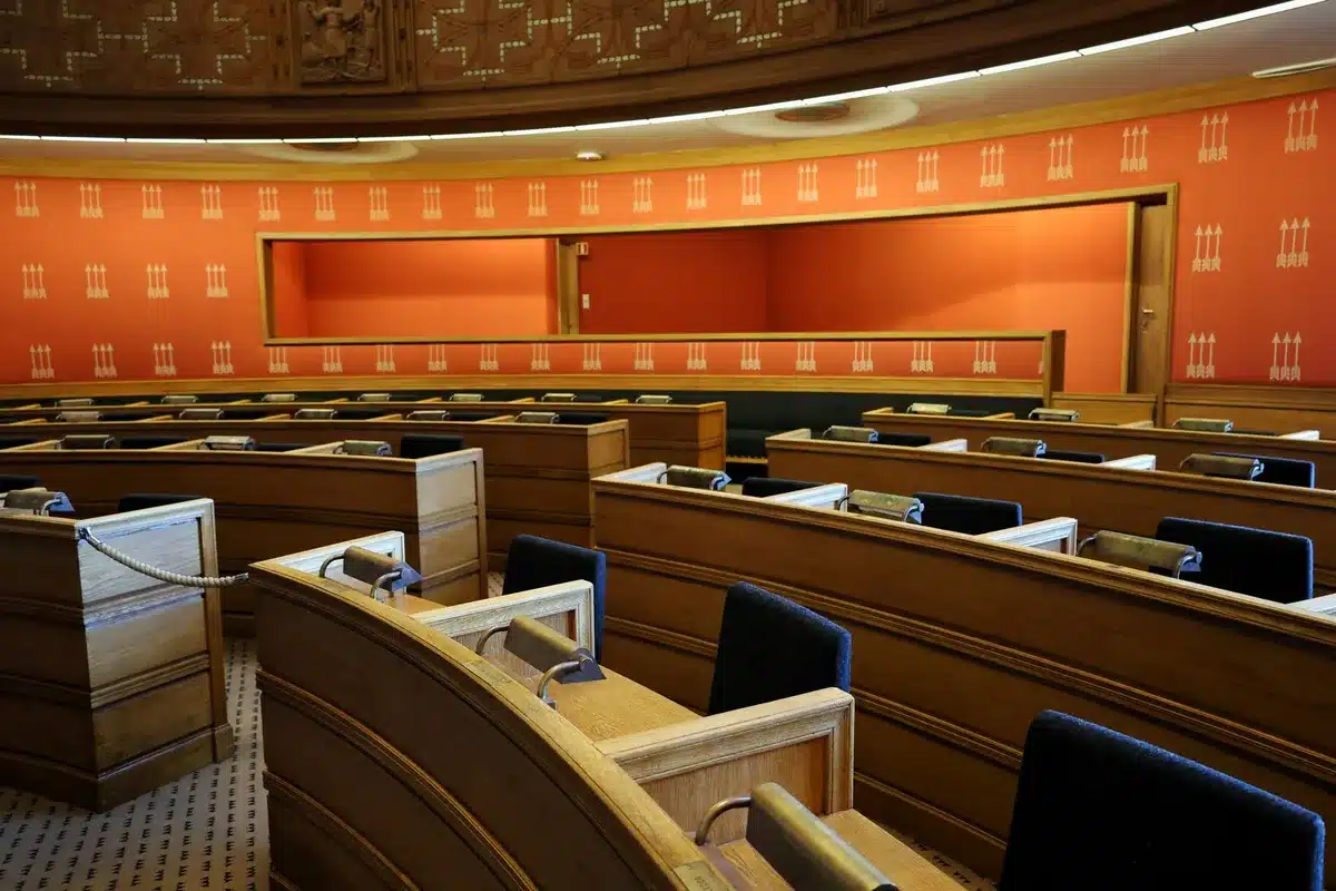 A formal Senate hearing room with a witness table and committee seating, empty chairs and microphones visible, institutional lighting and wooden paneling