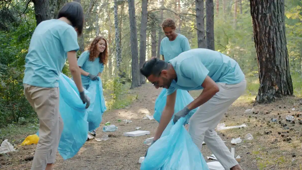 Samaritan's Purse volunteers in orange shirts working together in debris field, cutting fallen trees and clearing wreckage, focused on relief work