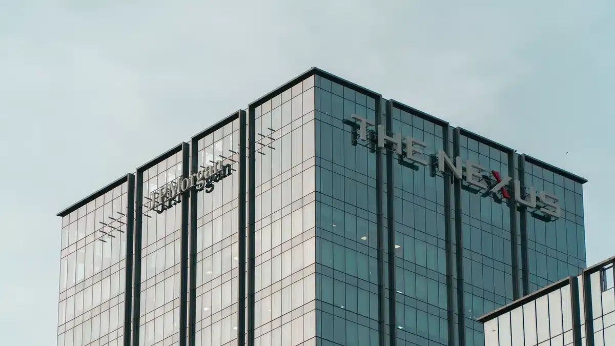 A modern glass office building at dawn, sunlight reflecting off its facade, symbolizing growth and scale in professional services.