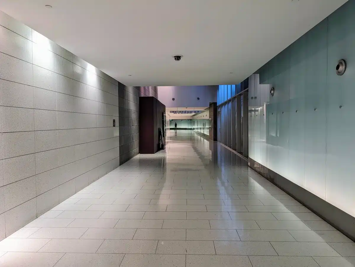 Empty Capitol building hallway, fluorescent lights casting cool shadows, a single doorway visible in distance, somber atmosphere