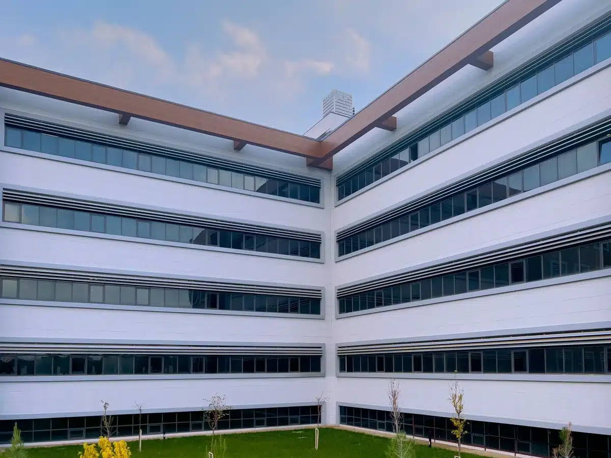 A hospital or medical office building exterior with administrative staff visible through windows, representing healthcare insurance operations and plan management decisions.