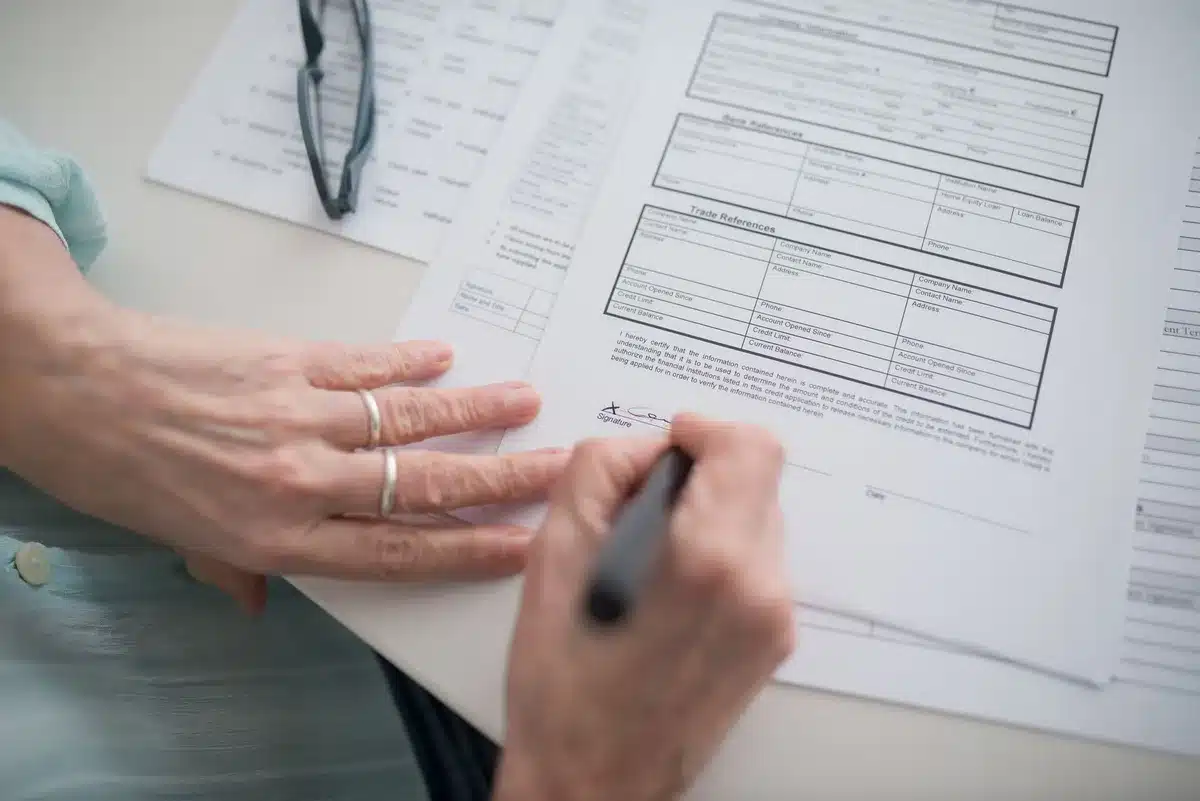A senior citizen reviewing healthcare paperwork at a desk, showing the human impact of plan changes and coverage decisions.
