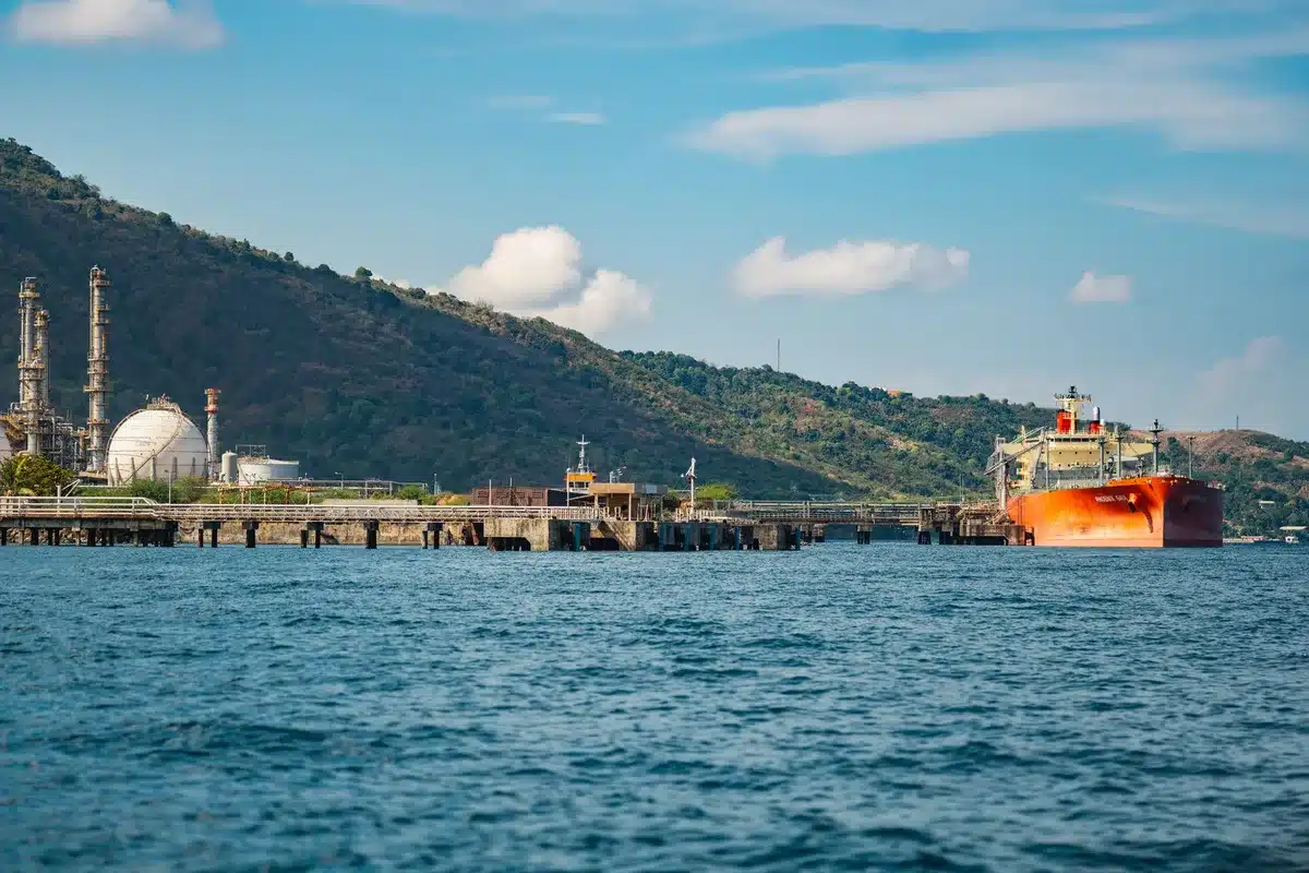 Shipping vessels navigating tense waters near the Strait of Hormuz, reduced traffic and empty shipping lanes, oil tankers moving cautiously through contested waterway