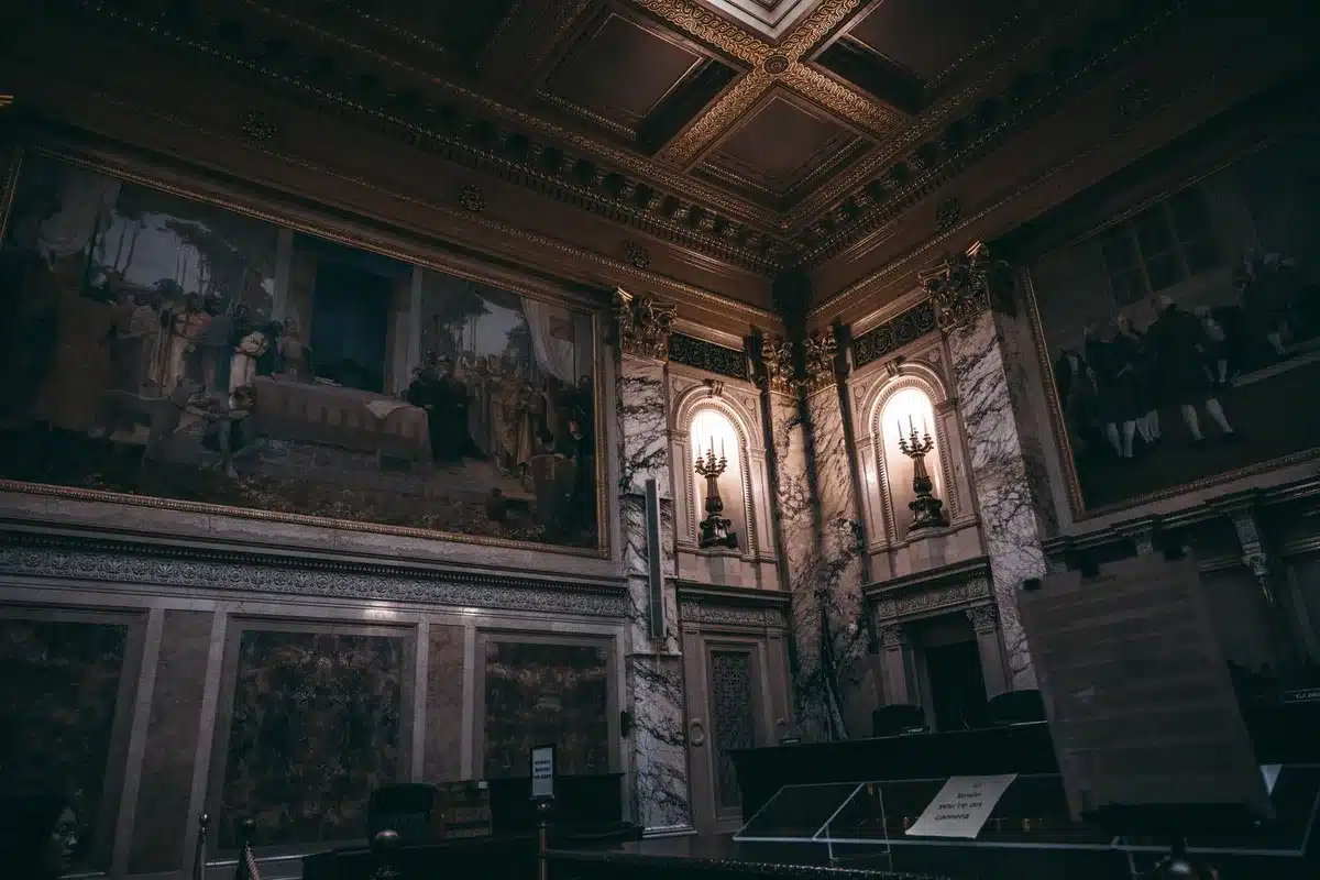 An anonymous figure in business attire walking through a Capitol hallway lined with classical columns and portraits, symbolizing institutional change