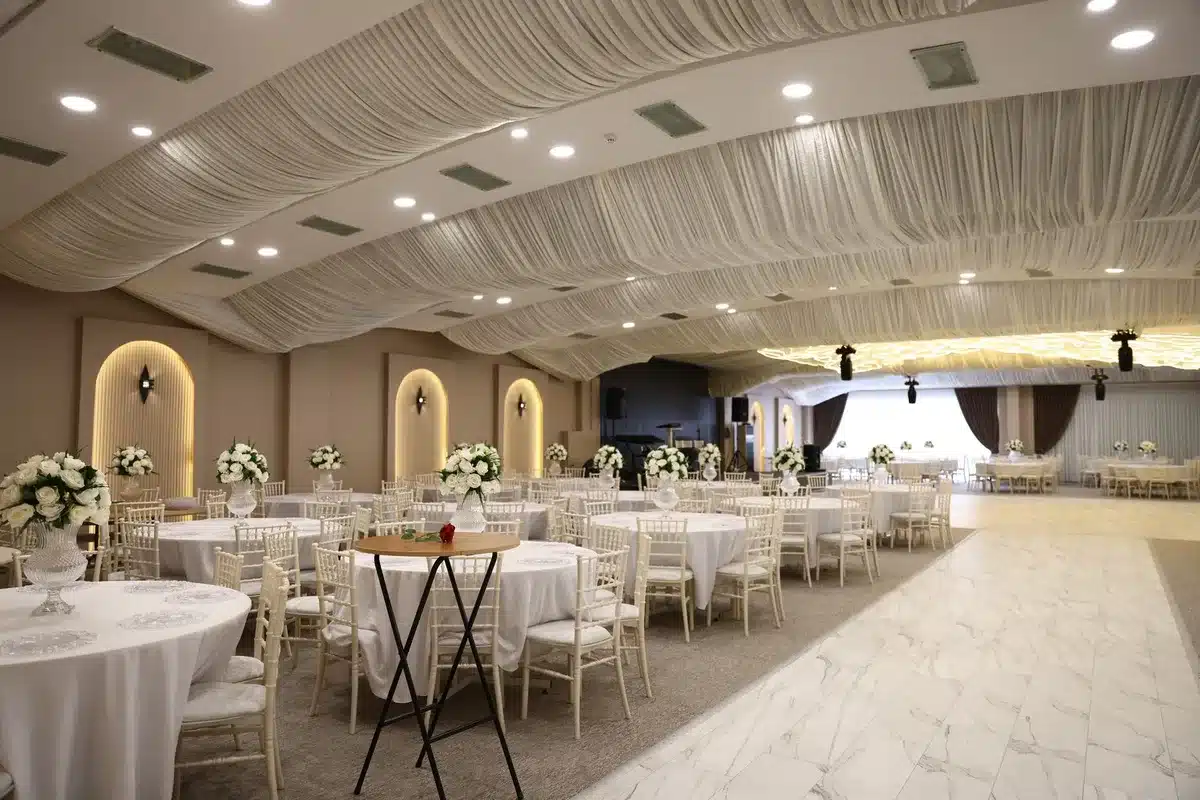 A formal ballroom setting with a podium and microphone, journalists seated at tables in evening wear, a spotlight illuminating the stage, the atmosphere tense and silent.