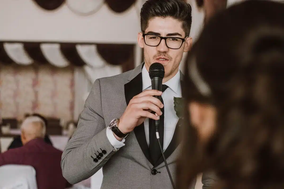 A broadcast journalist at a microphone during a formal White House event, composed and professional, surrounded by formal dinner setting with blurred officials in background, evening lighting