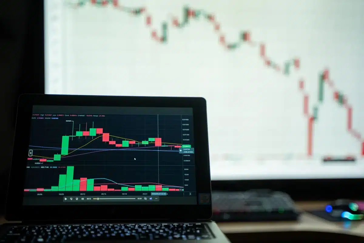 A stock trading floor with multiple monitors displaying red price charts, traders in motion, and a digital ticker showing sharp percentage declines in real time.