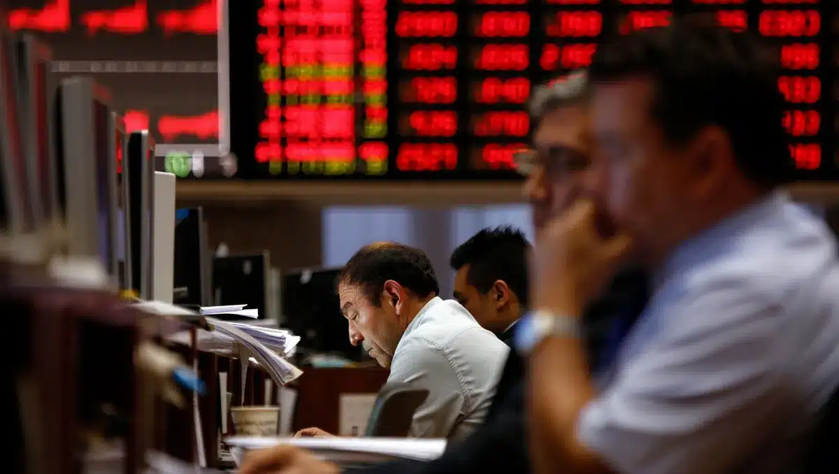 A dimly lit stock exchange trading floor with red ticker displays showing steep declines, anonymous traders hunched over terminals, scattered papers, and a single abandoned coffee cup on a desk&mdash;tension.