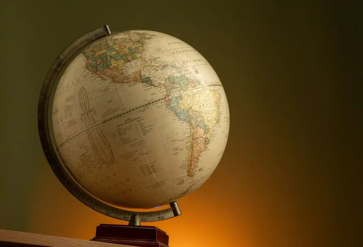 A desk with foreign policy documents, a globe, and photographs of international leaders in soft focus, a pen resting on open legislation, the accumulated weight of decades of diplomacy