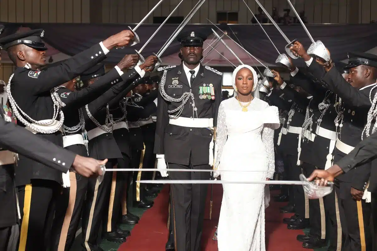 Woman in professional attire at a formal swearing-in ceremony, hand raised, Capitol backdrop, flags in background