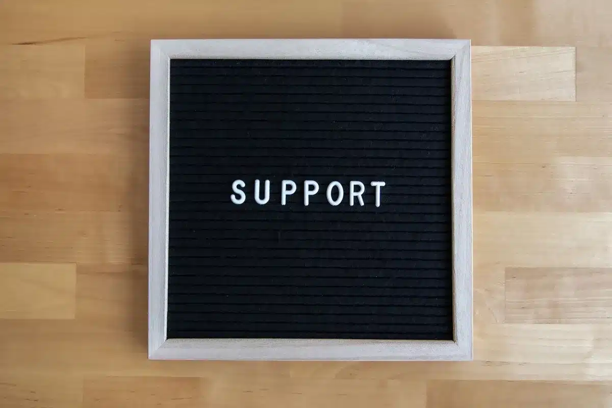 A laptop screen displaying mental health resources and support information, with a notebook and pen beside it in soft focus, suggesting online counseling or digital mental health support
