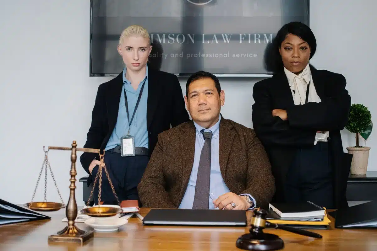 A diverse group of lawyers in business attire gathered outside a courthouse, some in conversation, representing the legal profession and the diversity Mamdani claims to have selected, with no identifiable faces in focus.