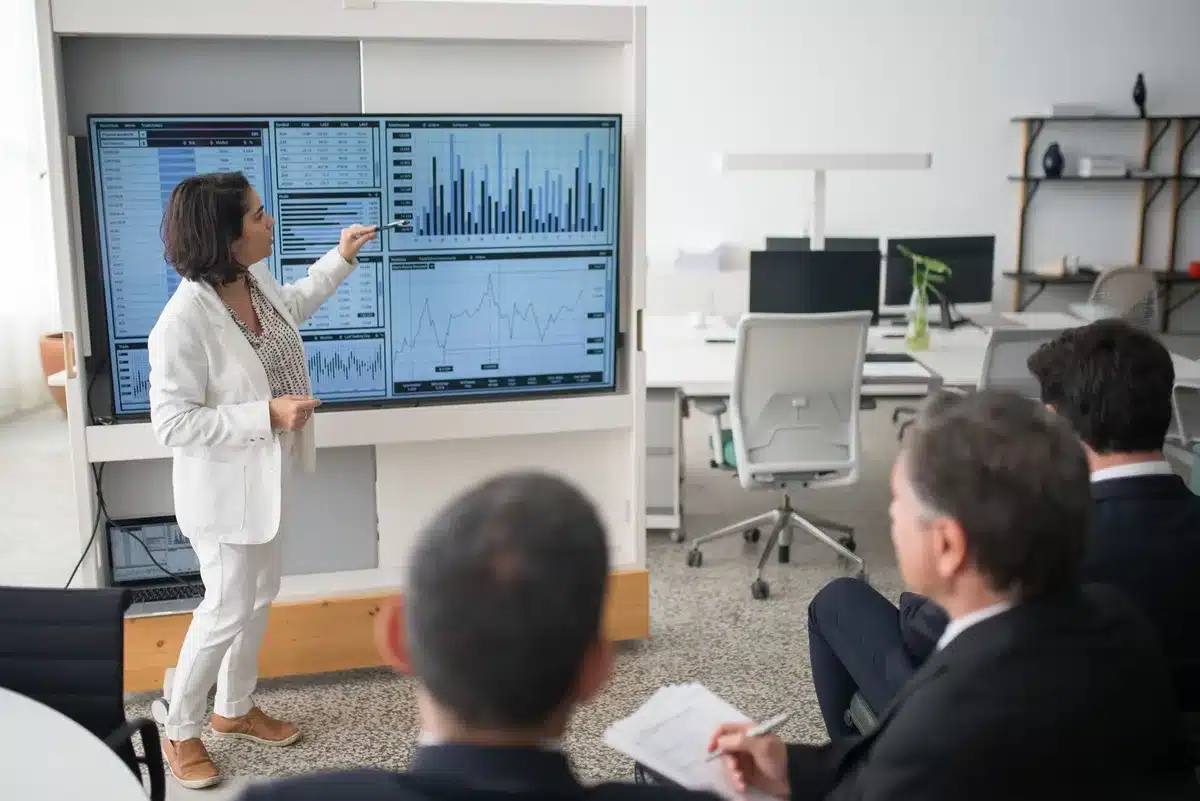 A corporate earnings presentation slide with a bar chart showing upward revenue trends, professional conference room setting with polished surfaces, subtle warm lighting on the data visualization, no people visible.