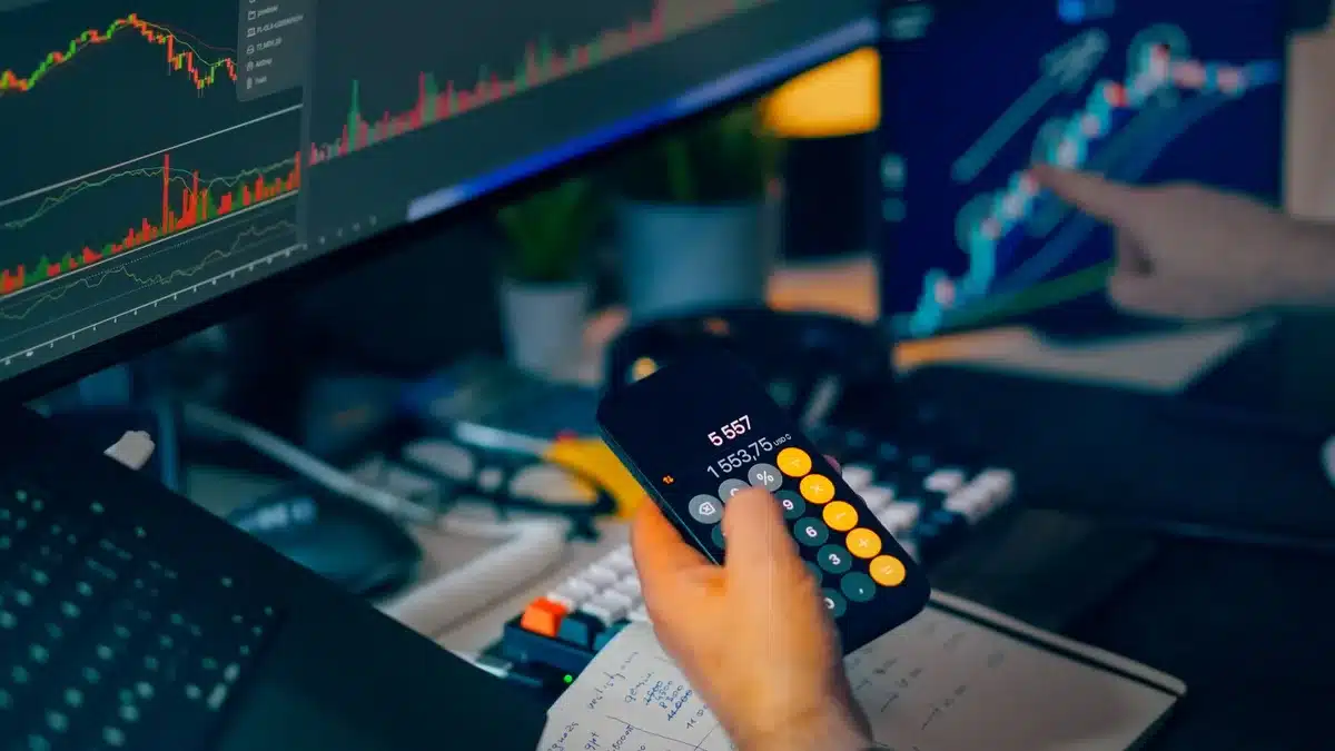 A glowing computer monitor displaying financial charts and text in a dark office setting, representing an investor's analytical workspace