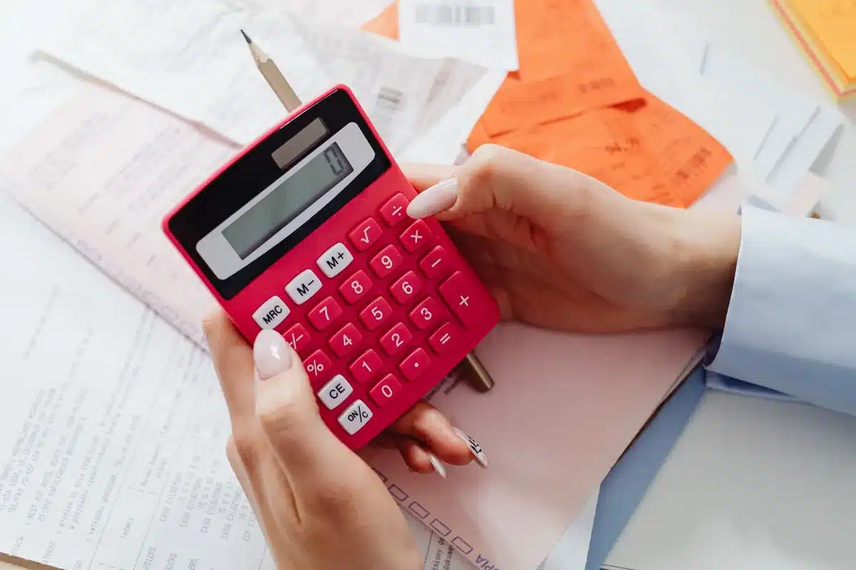 Close-up of a mortgage document with a pen, calculator, and rising interest rate chart visible on a desk