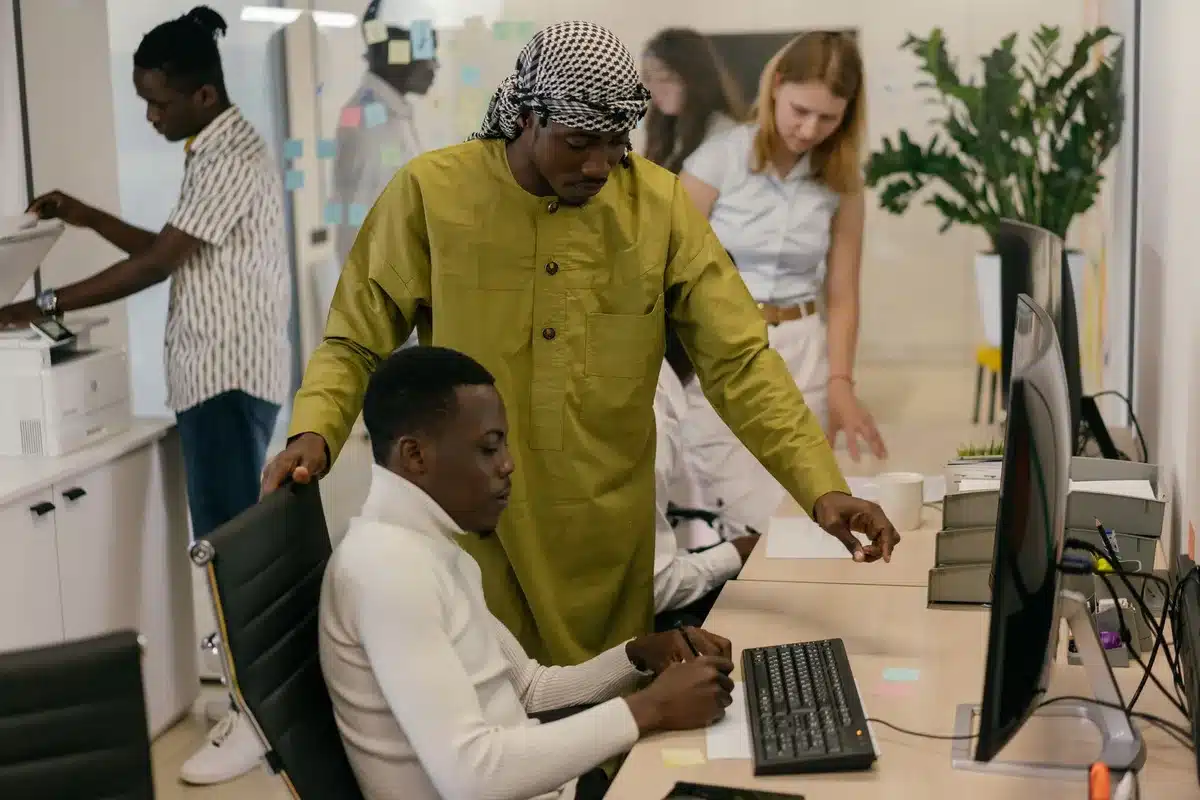 A diverse group of young professionals in an office environment participating in a collaborative team project, showing inclusion and mentorship in action.
