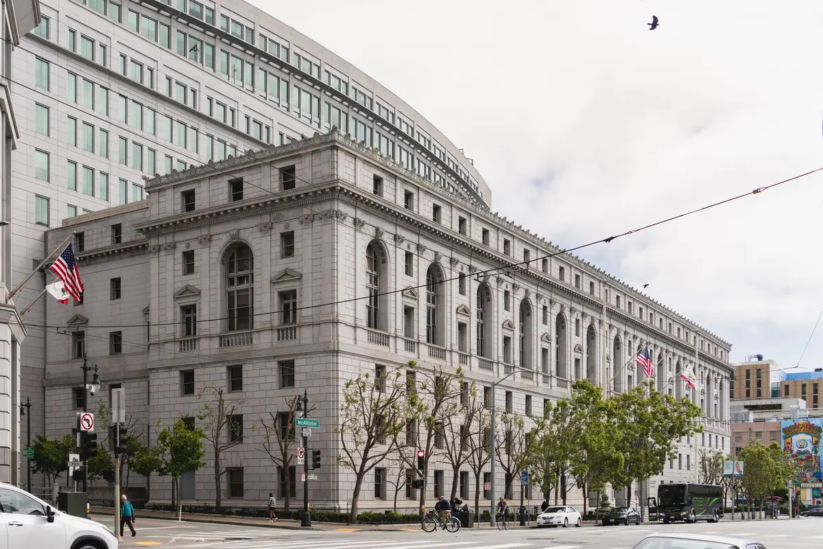 A federal courthouse entrance with classical columns and steps, neutral daylight, empty plaza, suggesting institutional authority and legal proceedings