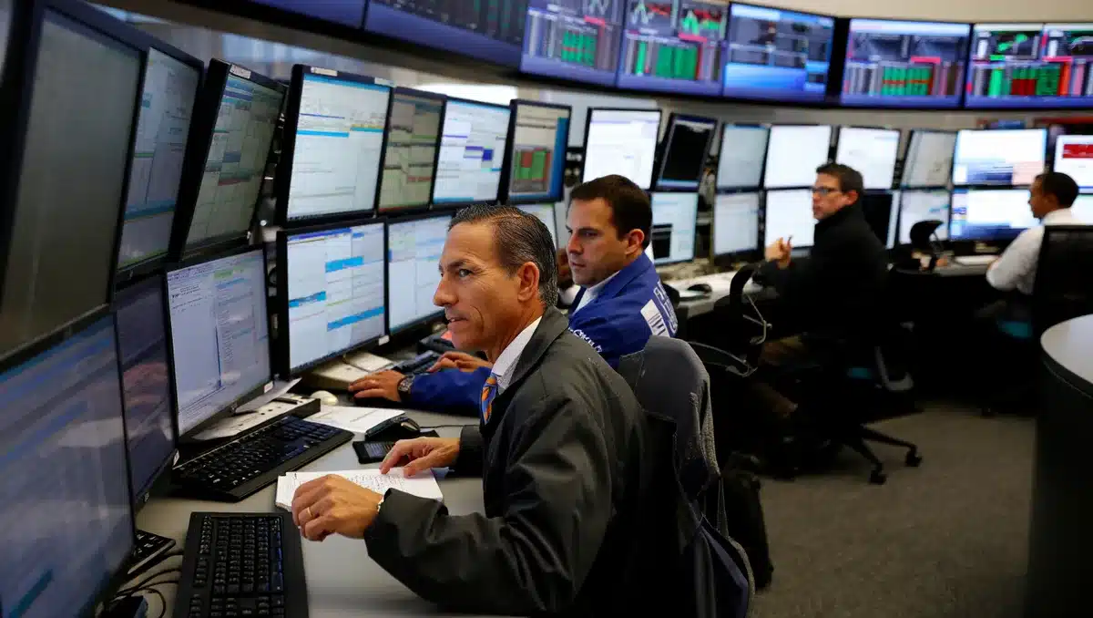 Stock market trading floor with multiple screens displaying financial data and charts, traders monitoring real-time price movements | financial trading floor