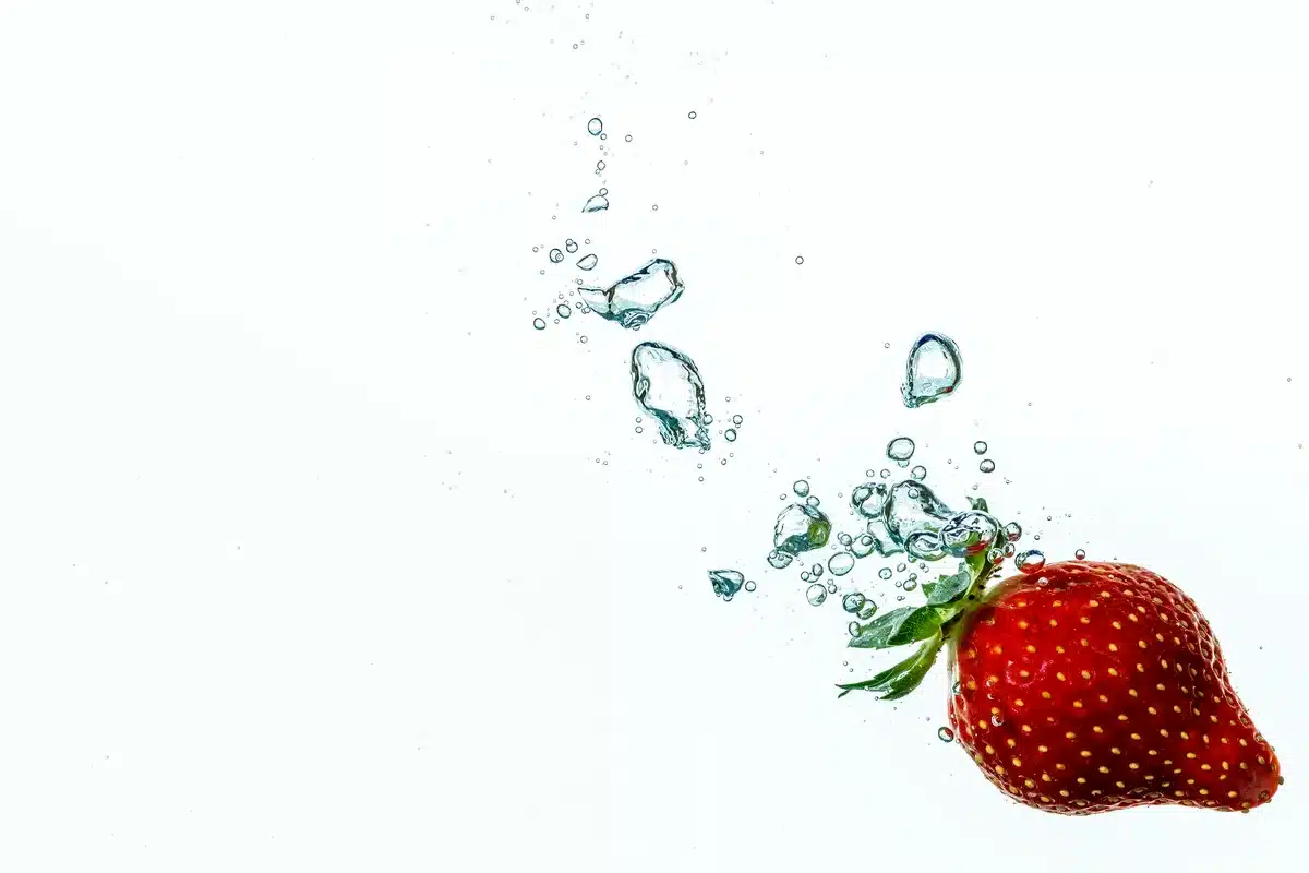 A close-up of a colorful fruit puree pouch on a white surface with barcode visible on the back, soft focus of grocery shelves in background