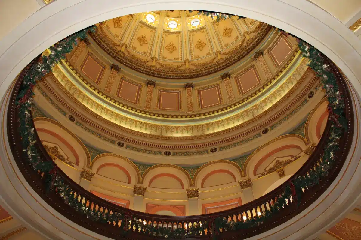 Capitol hallway with senators in conversation, natural light from windows, papers and folders visible, the atmosphere of behind-the-scenes legislative negotiation