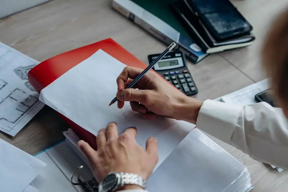 A desk with scattered financial documents, a calculator, and a laptop showing retirement planning spreadsheets, with a cup of coffee cooling nearby.
