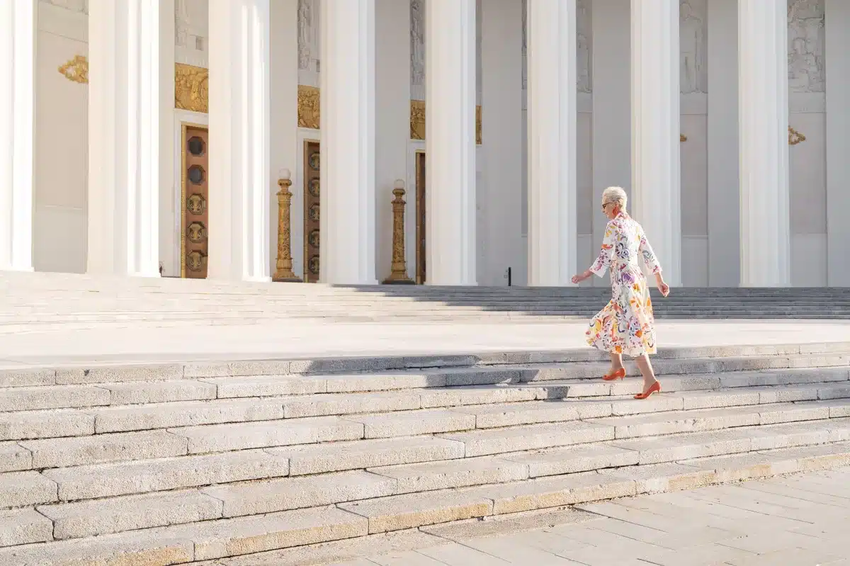 A marble-columned courthouse entrance with flags, sunlight streaming across the steps, an empty bench in the foreground