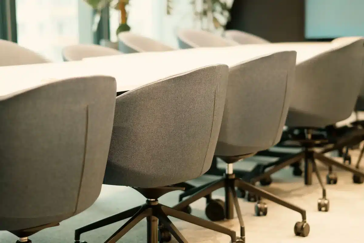 An empty FTC office chair at a polished desk, morning light through tall windows, documents and a nameplate visible but blurred