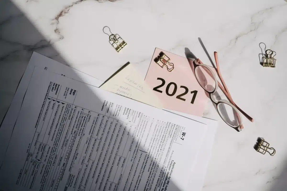 A stack of legislative documents and budget papers on a desk, with a calculator and pen, representing the fiscal debate