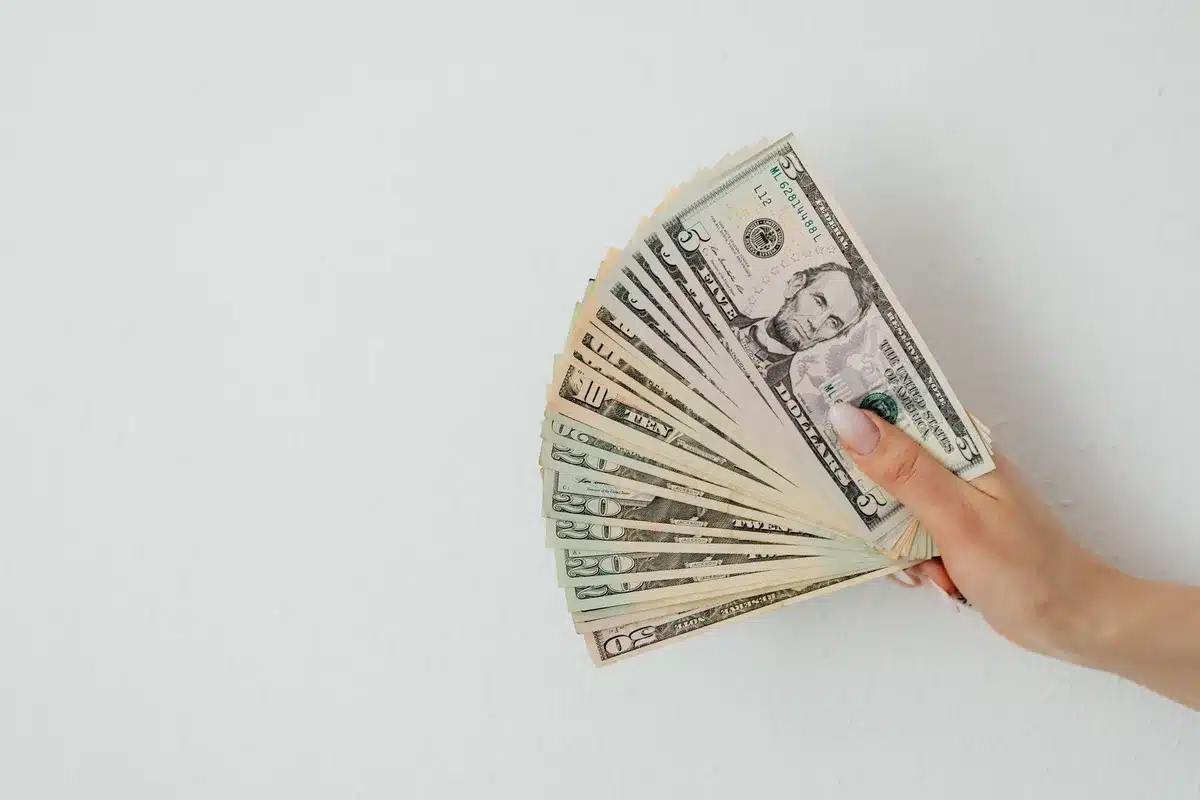 Elderly hands holding a Social Security card and monthly benefit statement, with a calculator and inflation chart visible on a table
