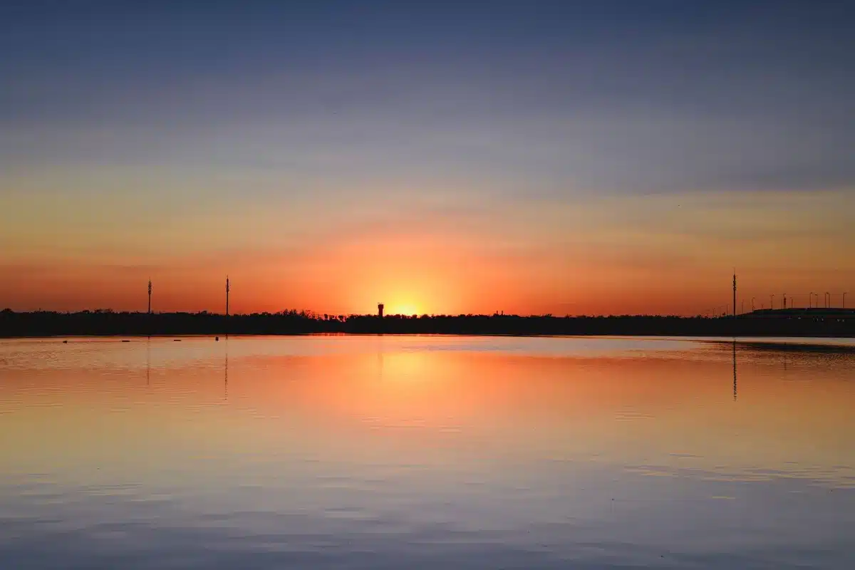 A Falcon 9 rocket on its launch pad at dawn, white body catching early light, launch tower silhouetted against a clearing sky, gantry arms retracted, ready for imminent liftoff.