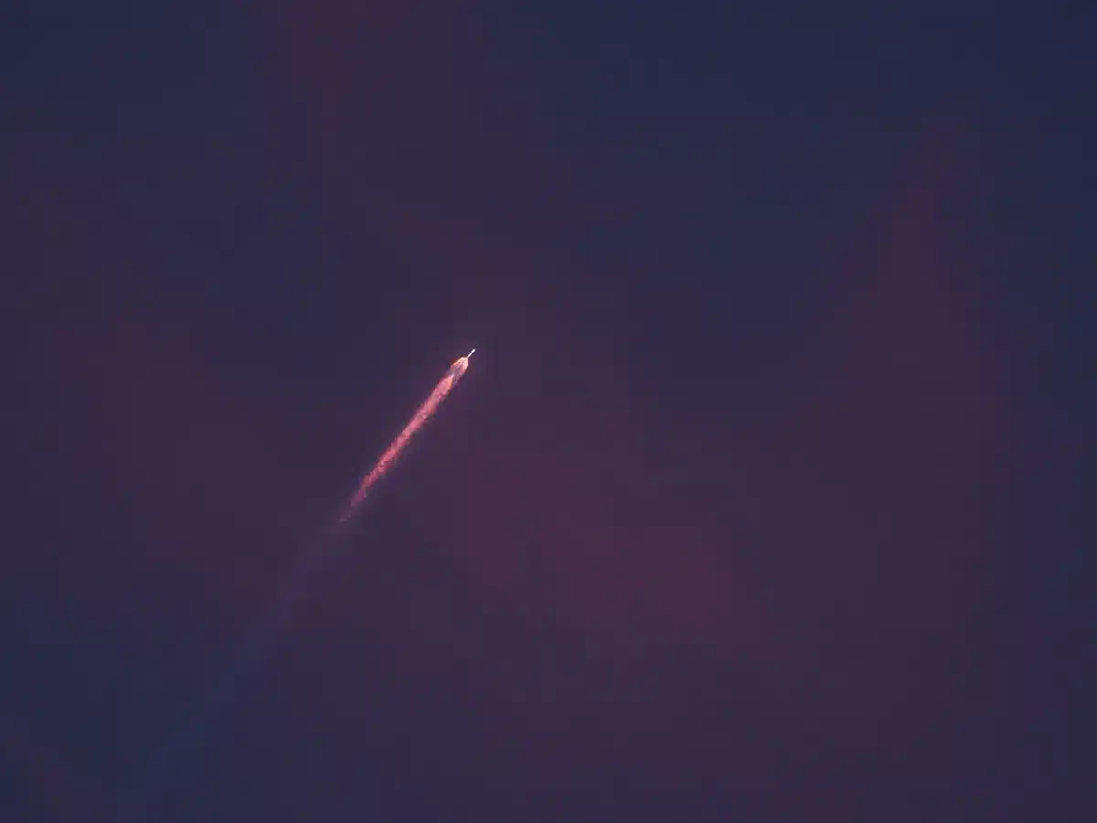A close-up of a Starlink V2 Mini satellite in the SpaceX facility, showing its solar panels, antennas, and body, under workshop lighting, emphasizing the engineering and technology behind the constellation.