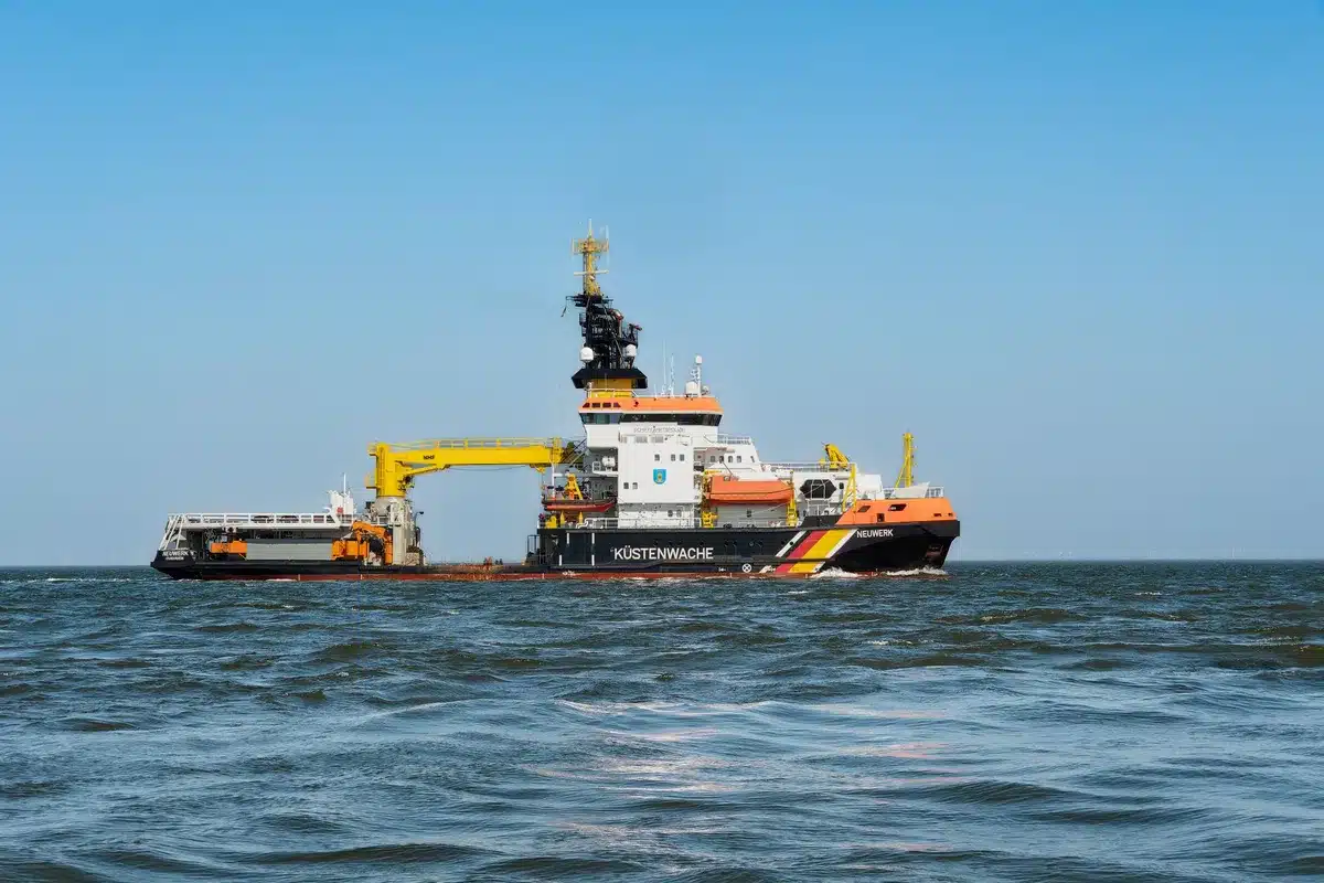A wide view of the Indian Ocean at dawn, with a distant rocket stage silhouette on the horizon, small recovery vessels approaching, golden sunlight reflecting off calm waters