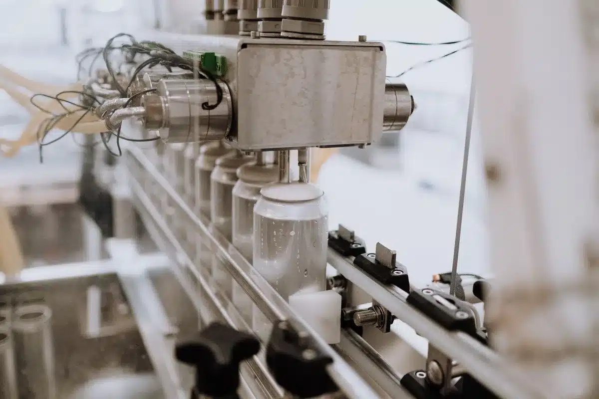 A Tesla Model 3 on a production line with manufacturing equipment visible in soft overhead lighting, conveying industrial scale and operational focus.